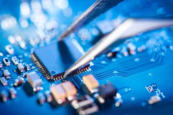 Electronic technician holding tweezers and assemblin