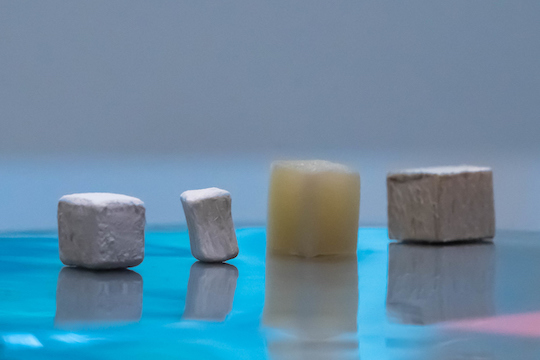 Wood pieces at different stages of modification, from natural (far right) to delignified (second from right) to dried, bleached and delignified (second from left) and MOF-infused functional wood.
