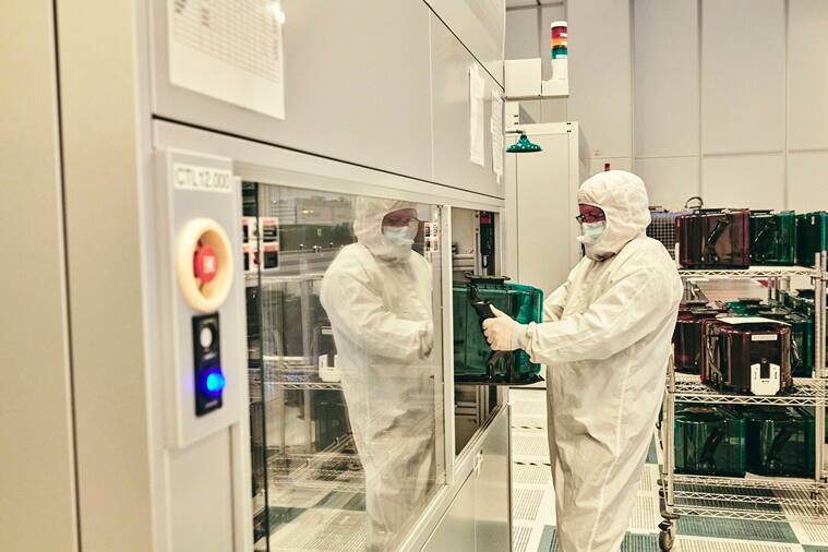 A worker handles a rack of silicon wafers from a chip-manufacturing machine at the IBM research facility in Albany