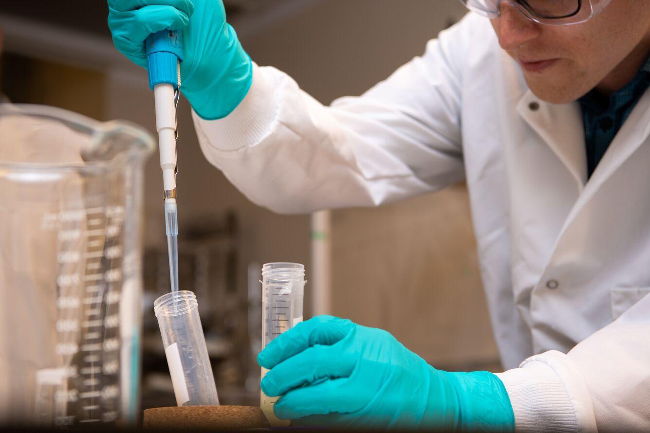 Caleb Allen transfers coronavirus-detecting micelles from one test tube to another. The yellowish color comes from linseed oil, which plays a critical role in the 279-step chemical process developed by PNNL scientists.